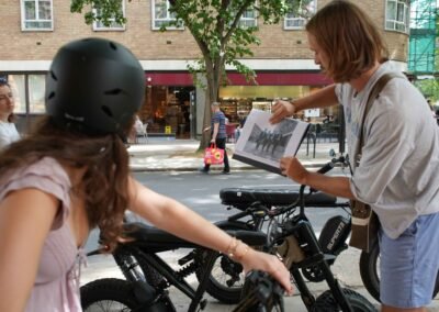 Guide showing Beatles archive photos to guests during a London e-bike tour with Super73 bikes.