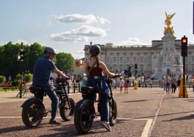FOF Bike Tours guests riding e-bikes in front of Buckingham Palace and the Victoria Memorial in London.