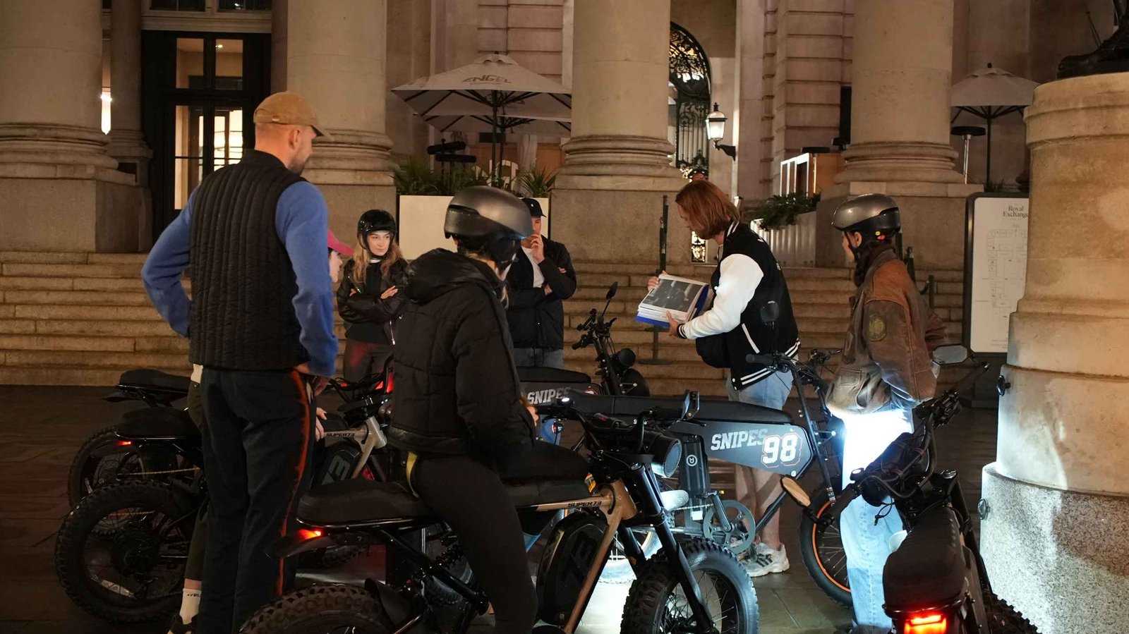 FOF Bike Tours guide showing historical material to guests during the Dickens Christmas e-bike tour at the Royal Exchange.